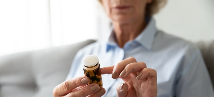 Mujer leyendo un envase de medicamento recetado​​ 