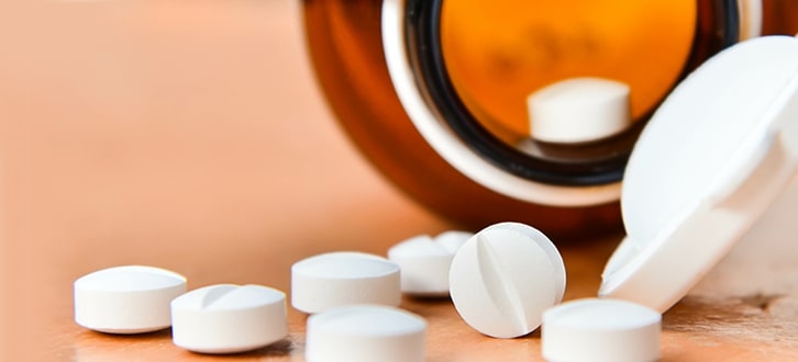 Un frasco de medicamento genérico derramado sobre una mesa​​  