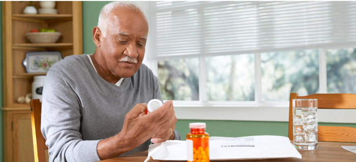 hombre leyendo el envase de un medicamento recetado​​ 