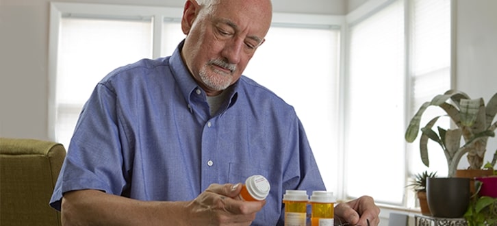 Cliente masculino de CenterWell Pharmacy revisando sus medicamentos en casa​​  