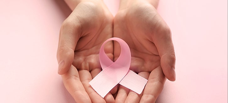 Lazo rosado del cáncer de mama en las manos​​ 