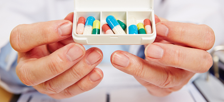 Farmacéutico sosteniendo un pastillero diario​​ 